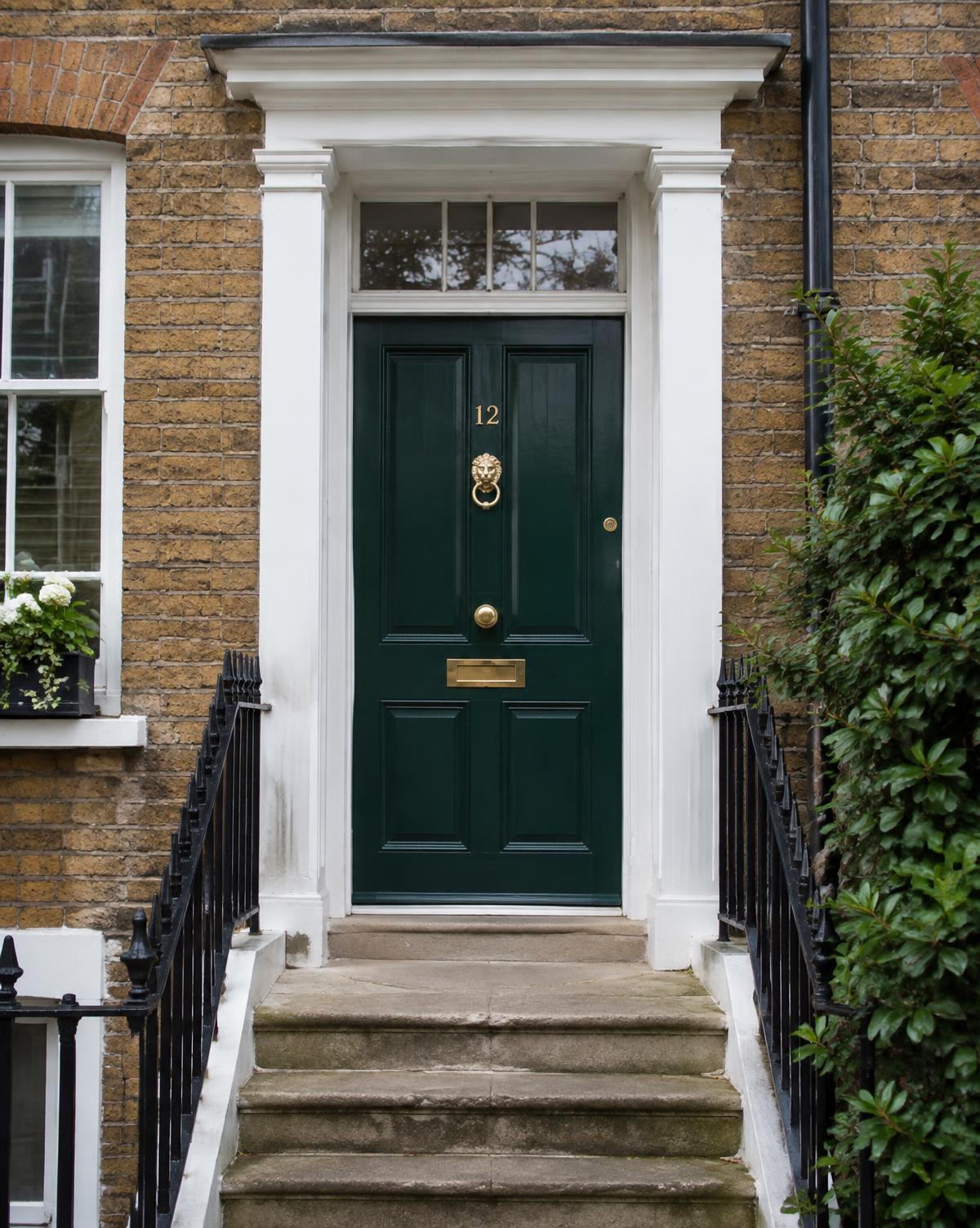 Dark green Georgian front door with brass knocker on a London brick townhouse